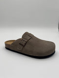A single taupe-brown suede clog-style mule shoe with a double-buckle strap and a black sole, photographed on a light gray studio background.