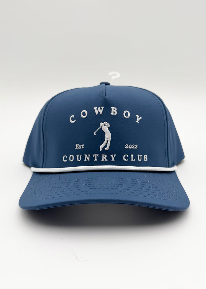 A navy blue baseball cap with white embroidered text reading 'COWBOY COUNTRY CLUB' and a white golfer silhouette, shown on a light gray studio background.