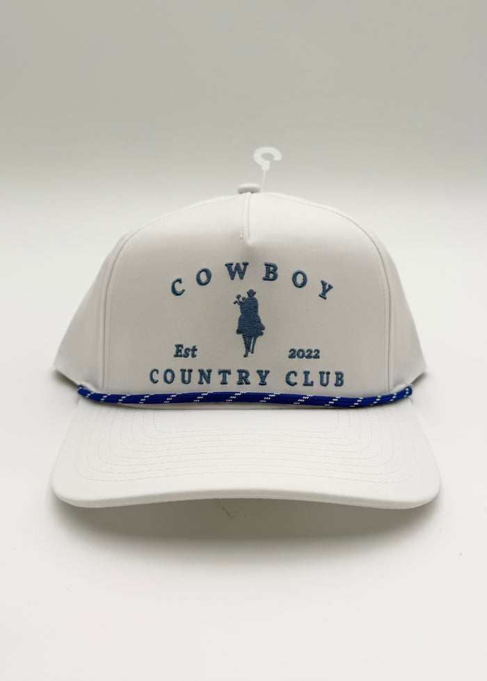 A white baseball cap with a blue rope detail along the brim and navy blue embroidered text reading 'COWBOY COUNTRY CLUB' with a cowboy silhouette, shown on a light gray background.