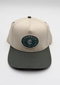 A structured baseball cap with a light beige crown and a dark gray flat brim, featuring an oval patch on the front that reads 'COWBOY COUNTRY CLUB'.
