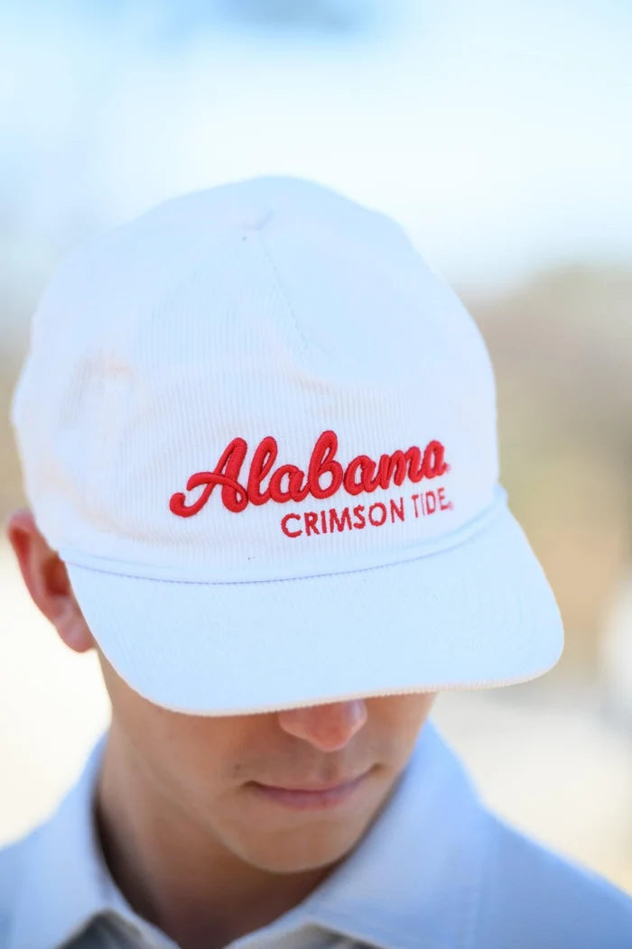 A white baseball cap with red embroidered 'Alabama CRIMSON TIDE' text, worn by a person outdoors with a blurred light background.