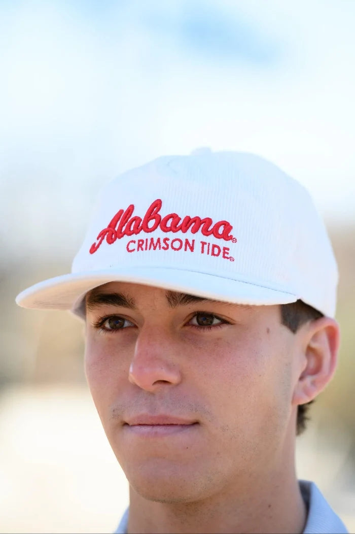 Person wearing a white cap with 'Alabama Crimson Tide' text against a blurred background