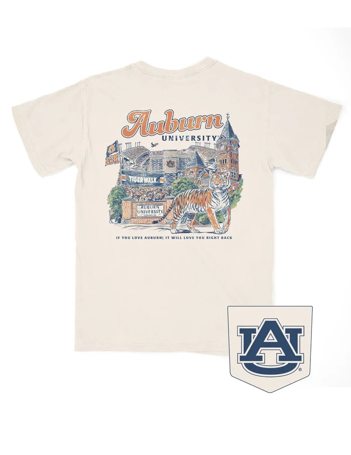 An off-white short-sleeve t-shirt featuring a large graphic print on the back with 'Auburn University' in orange script, a vintage building illustration, a tiger, and the Auburn 'AU' logo patch shown below the shirt.