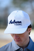 Person wearing a white 'Auburn Tigers' cap outdoors
