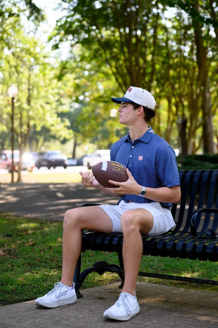 Person sitting on a bench holding a football in a park-like setting