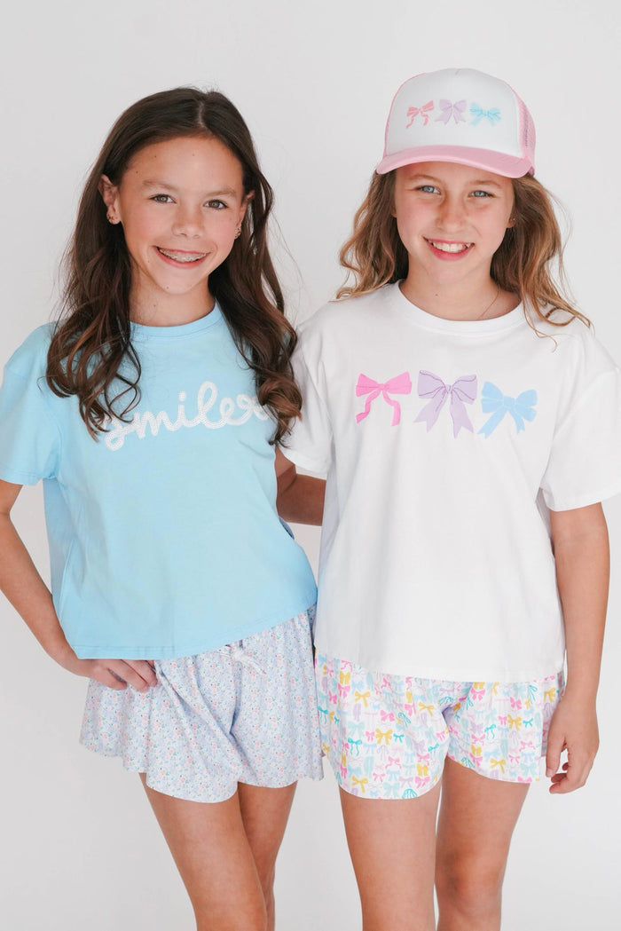Two young girls wearing matching outfits with colorful designs on a white background