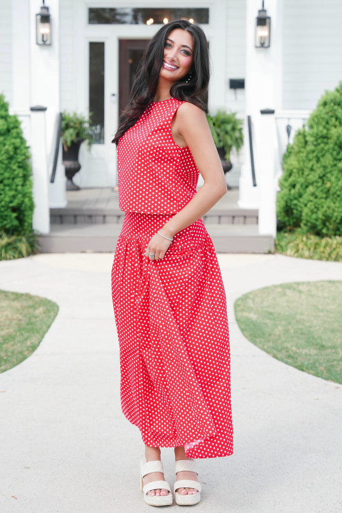 Woman wearing a red polka dot dress standing outdoors.