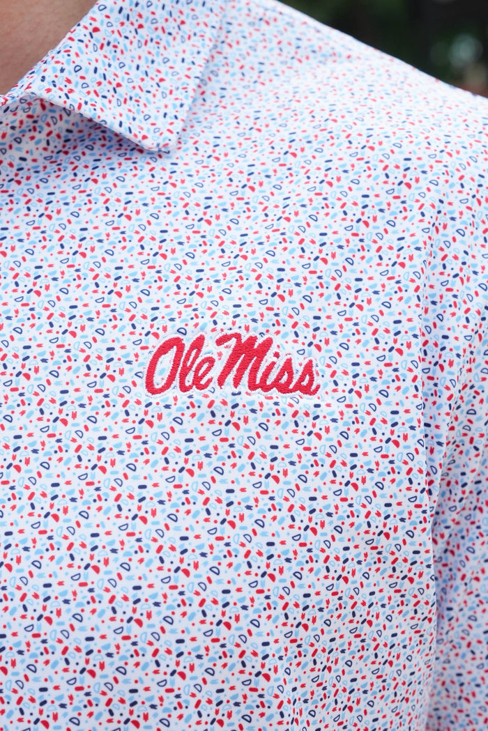 Close-up of a white short-sleeve button-up shirt with a dense red, blue, and black micro-pattern, featuring the red script 'OleMiss' logo on the chest.