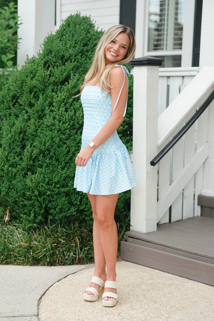Woman in a light blue dress standing on a porch
