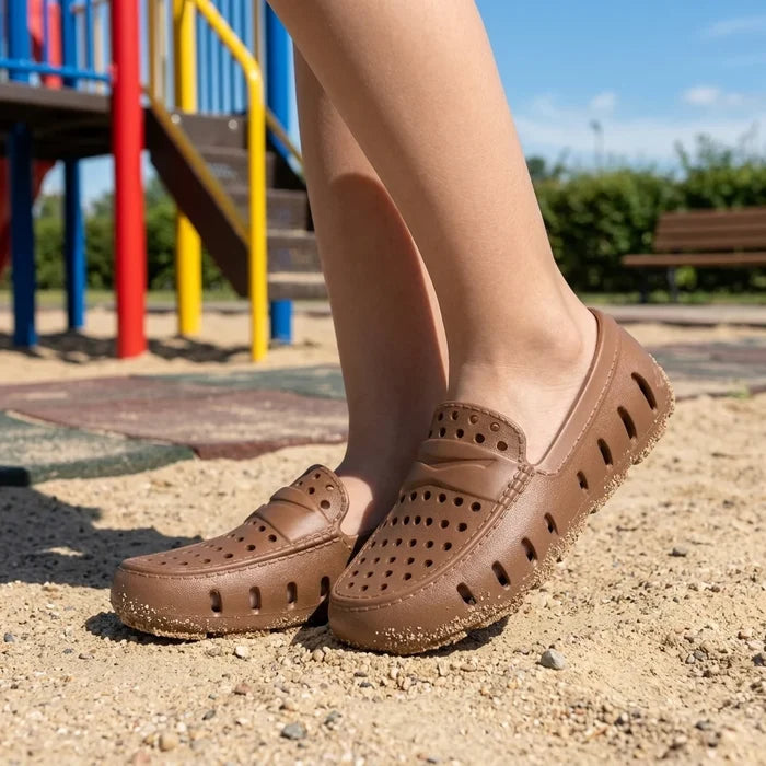 Brown clogs worn outdoors with playground equipment in the background