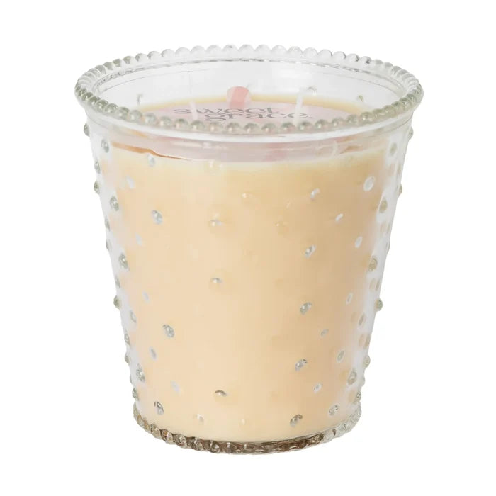 Candle in a decorative glass holder with a beaded rim on a white background