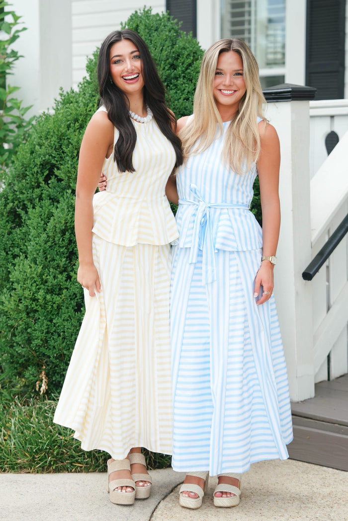 Two women in white and light blue dresses standing outdoors.
