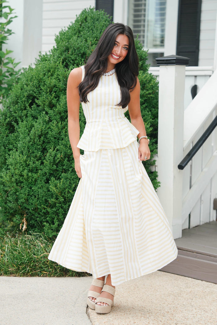 Woman in a white dress standing outdoors near a house.