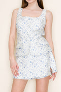 Woman wearing a light blue floral dress against a plain background