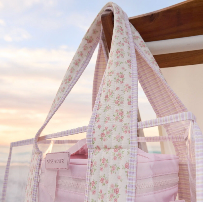 Floral-patterned tote bag with a visible brand name against a blurred natural background