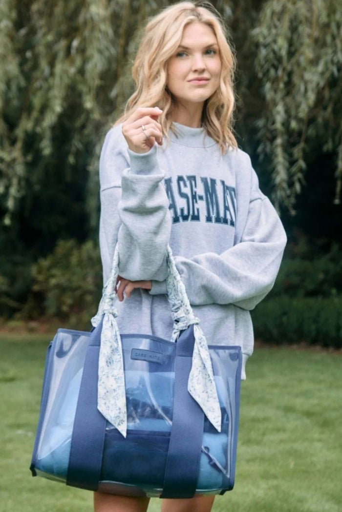 Woman wearing a 'Case-Mate' sweatshirt holding a large blue tote bag outdoors.