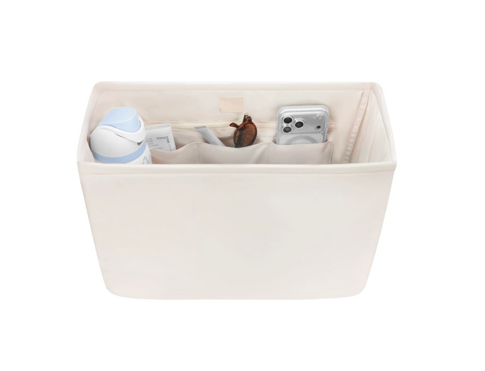 Beige fabric storage basket with compartments containing various items on a white background