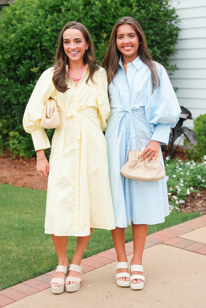 Two women in pastel-colored dresses standing outdoors on a sidewalk.