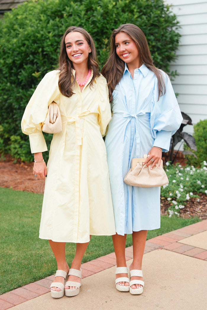 Two women in pastel-colored dresses standing outdoors on a sidewalk.
