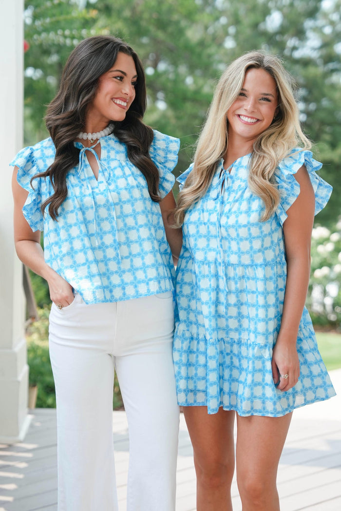 Two women wearing matching blue checkered outfits standing outdoors.