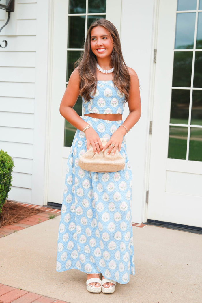 Woman in a blue floral dress standing outside a house