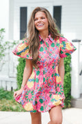 Woman wearing a colorful floral dress standing outdoors.