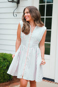 Woman wearing a green and white striped dress standing outdoors.