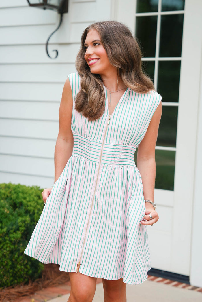 Woman wearing a green and white striped dress standing outdoors.