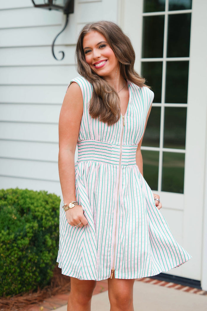 Woman wearing a striped dress standing outside a house.