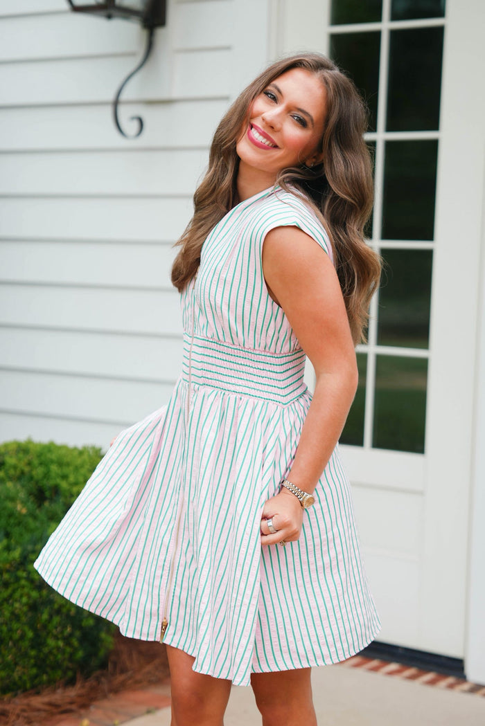 Woman wearing a green and white striped dress standing in front of a house.