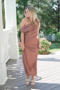 Woman in a polka dot dress standing on a wooden deck with greenery in the background