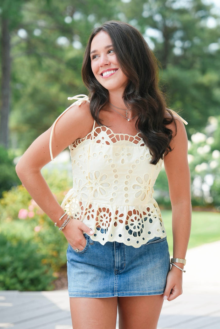 Woman wearing a white lace top and denim shorts outdoors