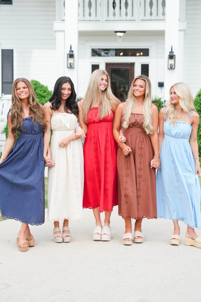 Five women in colorful dresses standing in front of a house.
