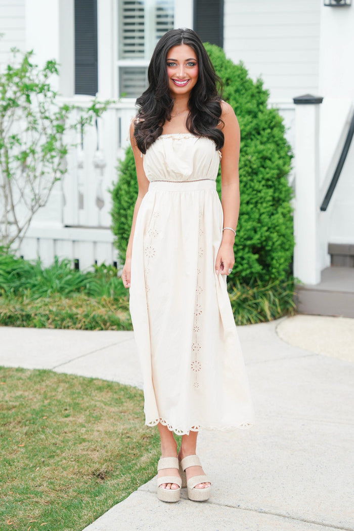 Woman in a white dress standing outdoors on a sunny day.