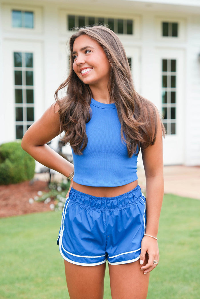 Woman wearing a blue athletic outfit standing outdoors.