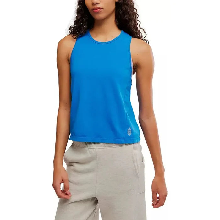 Person wearing a blue sleeveless top and beige pants on a white background