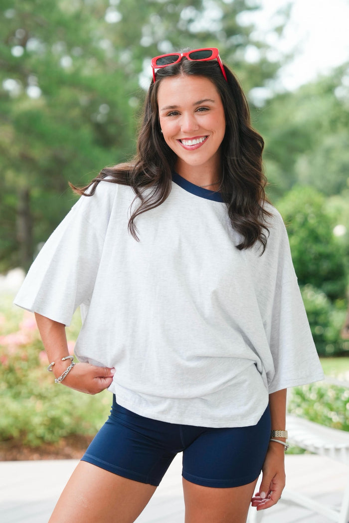 woman standing wearing a grey tee and navy shorts