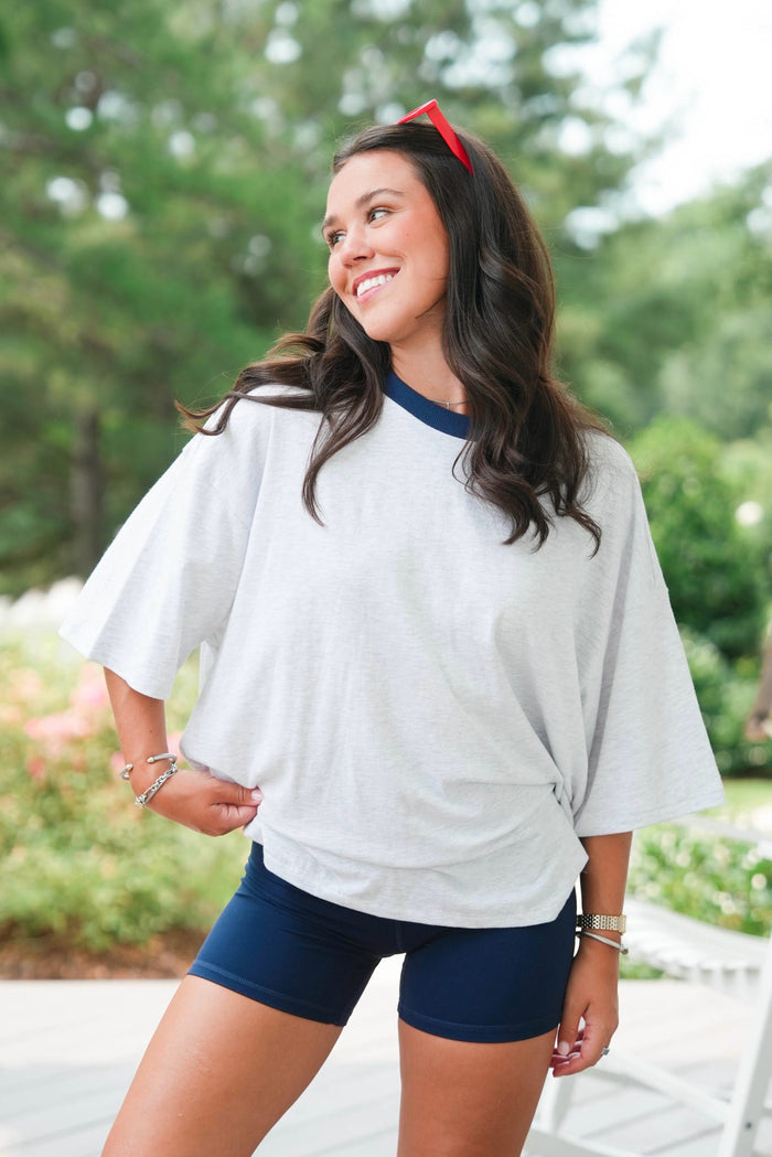 woman standing wearing a grey tee and navy shorts