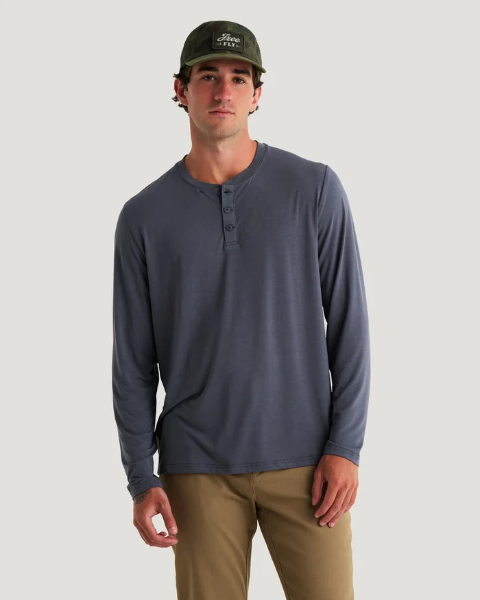Man wearing a long-sleeve henley shirt and cap on a plain background