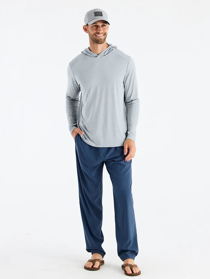 Man wearing a gray long-sleeve shirt and blue pants on a white background