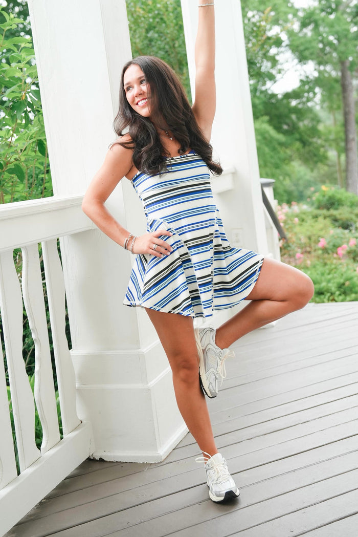 Woman in a striped dress posing on a wooden deck with greenery in the background