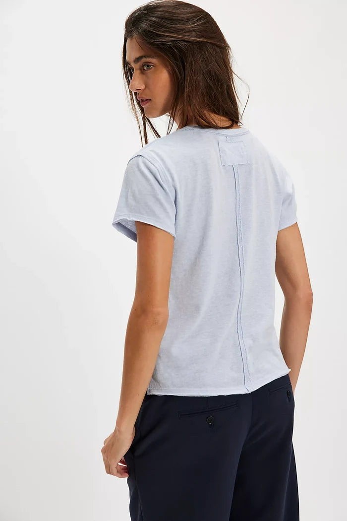 Woman wearing a light blue t-shirt and dark pants on a white background