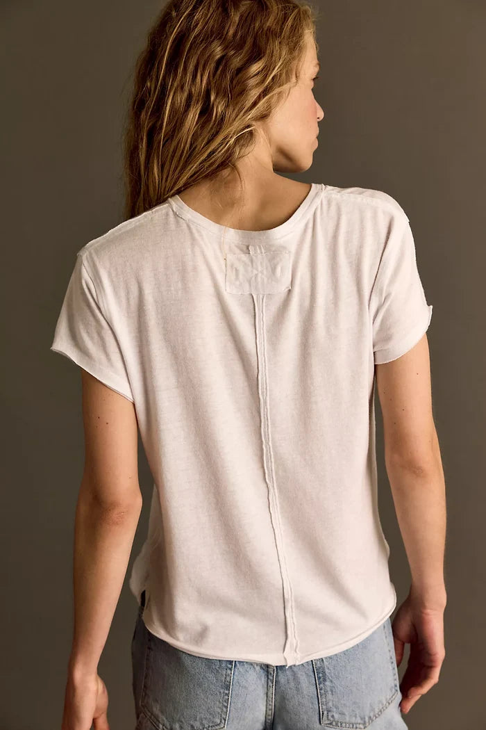 Person wearing a plain white t-shirt and light blue jeans against a neutral background