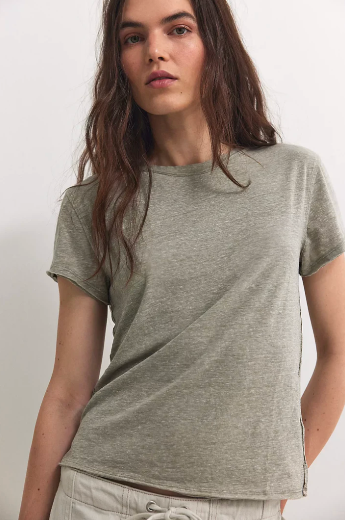 A woman wearing a short-sleeve crewneck t-shirt in heather gray, paired with light beige drawstring pants, photographed against a plain off-white background.