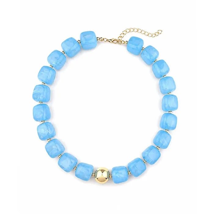 A beaded necklace featuring light blue faceted square beads separated by small gold spacer rings, with a central gold bead and a gold chain extender clasp, shown on a plain white background.