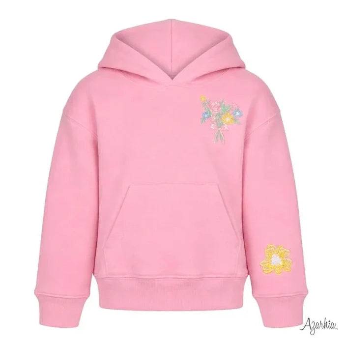 A pink pullover hoodie with a small multicolor floral embroidery on the left chest and a yellow flower embroidery on the right sleeve, shown against a plain white background.