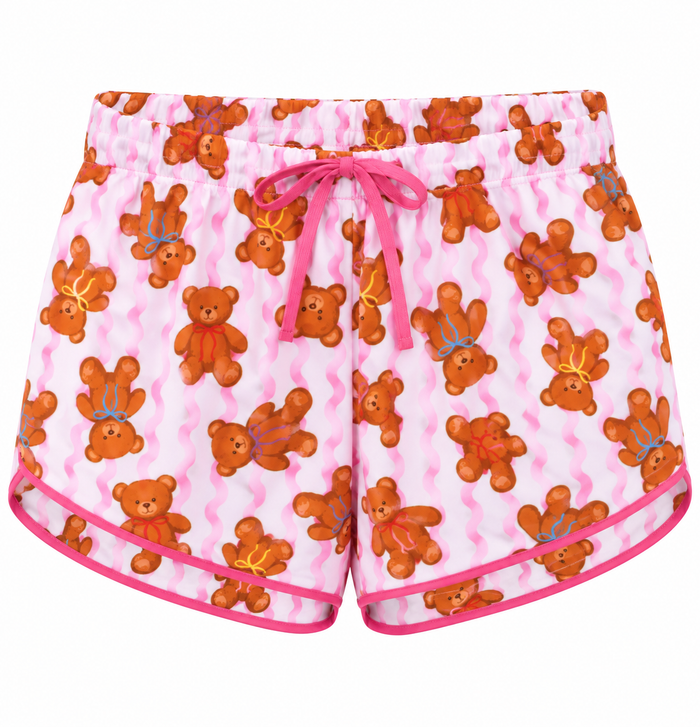 Pink and white wavy-patterned shorts featuring an all-over print of brown teddy bears, with a pink drawstring waist and pink piping along the hem.