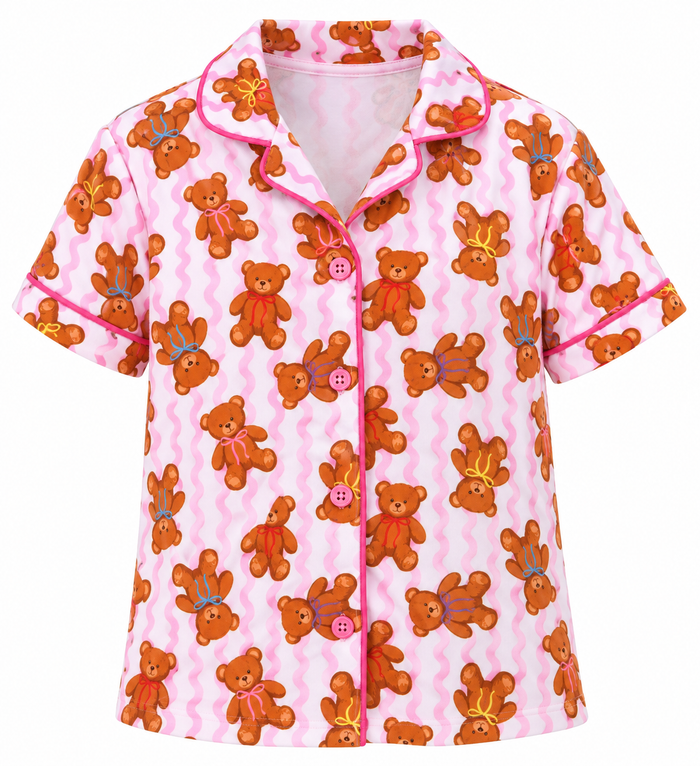 A short-sleeve pajama shirt with a pink and white wavy stripe background, featuring an all-over print of brown teddy bears wearing small crowns and bows, with pink piping and buttons.