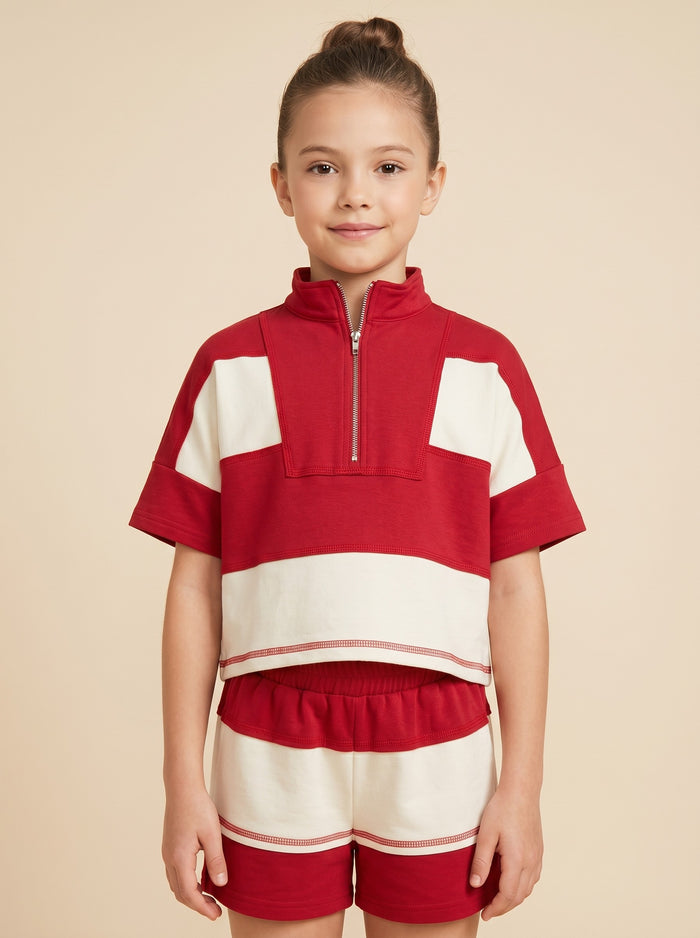 Young girl wearing a red and white outfit with a beige background