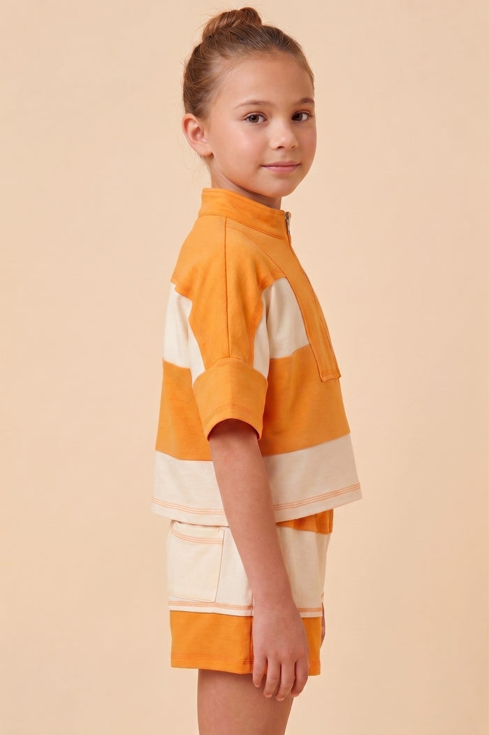 Young girl wearing an orange and white striped dress on a beige background